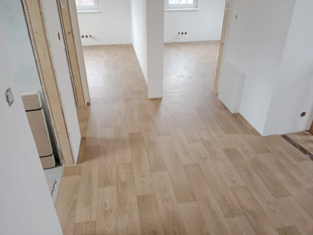 Hotová světlá dřevěná podlaha propojující dvě místnosti bytu